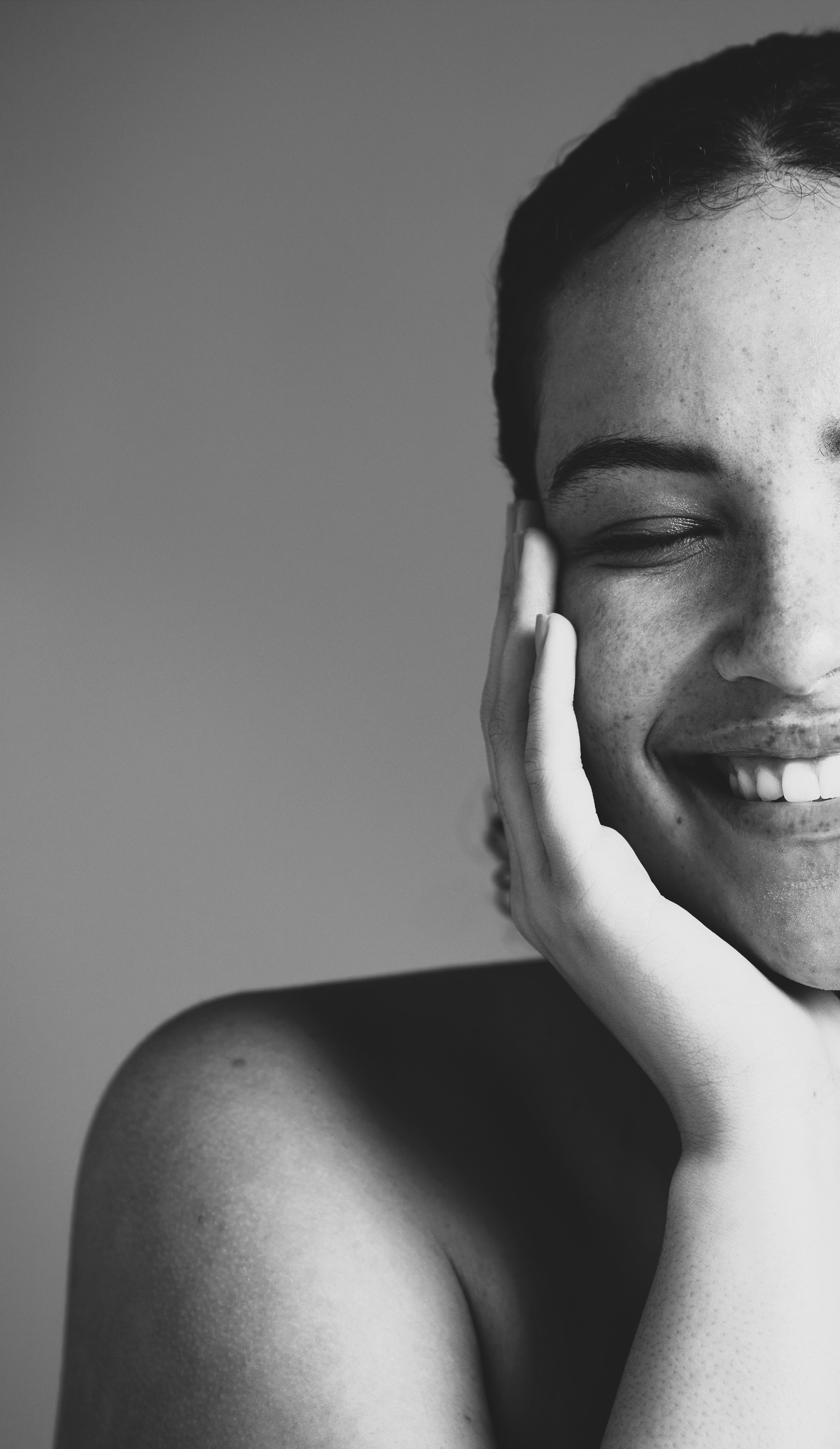 An image of a woman with a radiant, makeup-free, and freshly washed face, smiling with a natural, glowing complexion